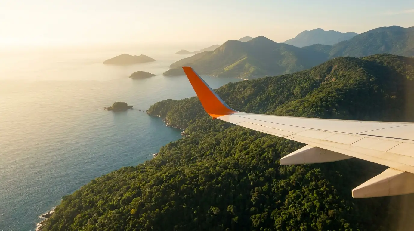 Ala de avión sobrevolando la costa al atardecer